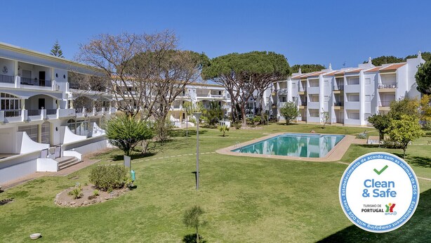 Un hôtel composé de plusieurs bâtiments blancs, doté d’une piscine et d’une pelouse bien entretenue.