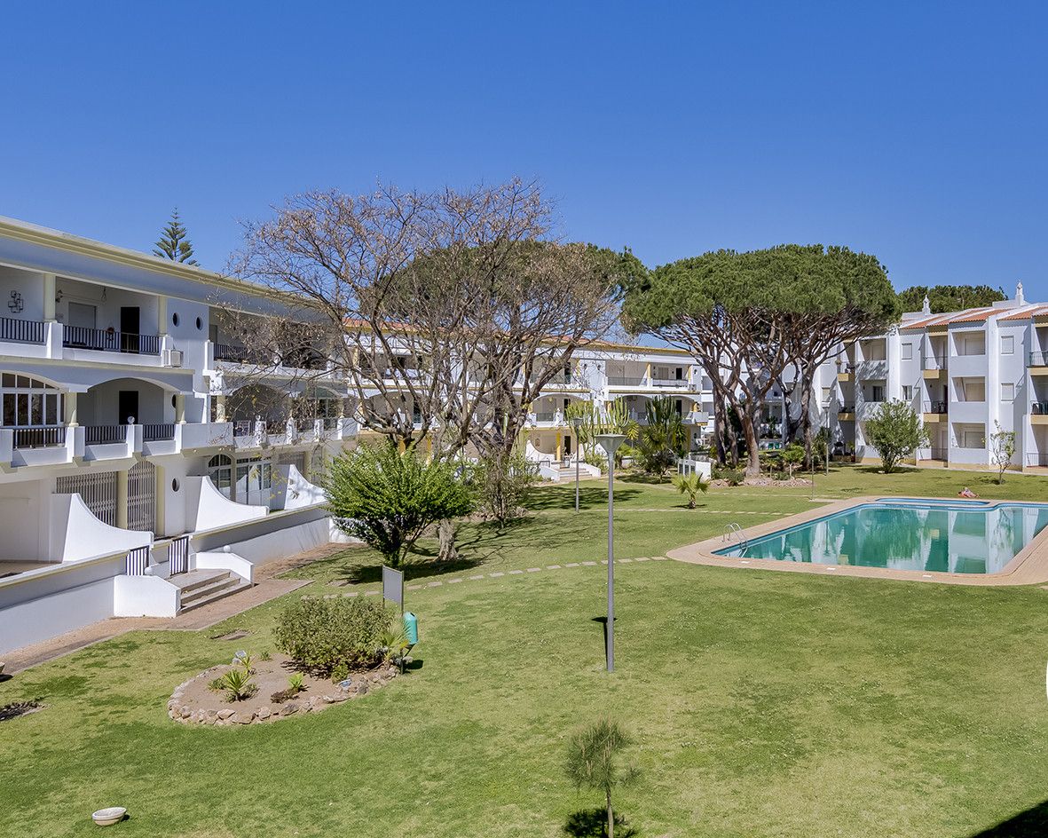 A hotel with multiple white buildings, a swimming pool, and a well-maintained lawn.