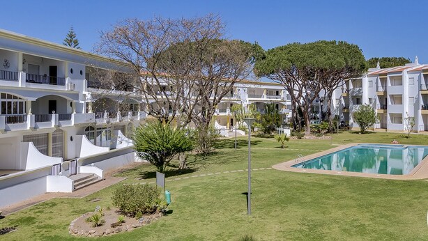 Un hotel con varias edificaciones blancas, piscina y césped bien cuidado.