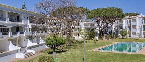 A hotel with multiple white buildings, a swimming pool, and a well-maintained lawn.