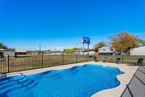 A swimming pool with a fence, a sign for Rodeway Inn, and RVs in the background. - Rodeway Inn Kingsland - Lake LBJ (Kingsland)