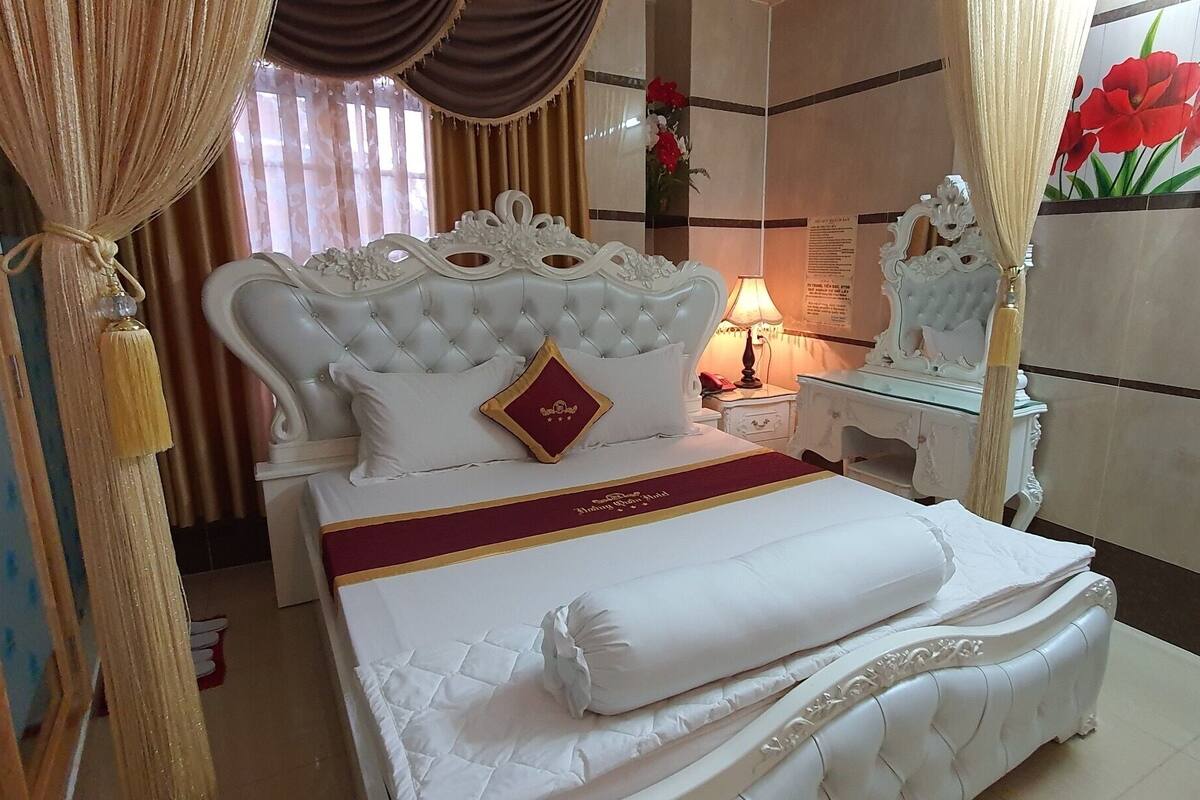 Une chambre d’hôtel avec un grand lit, une table de chevet, un miroir et des rideaux.