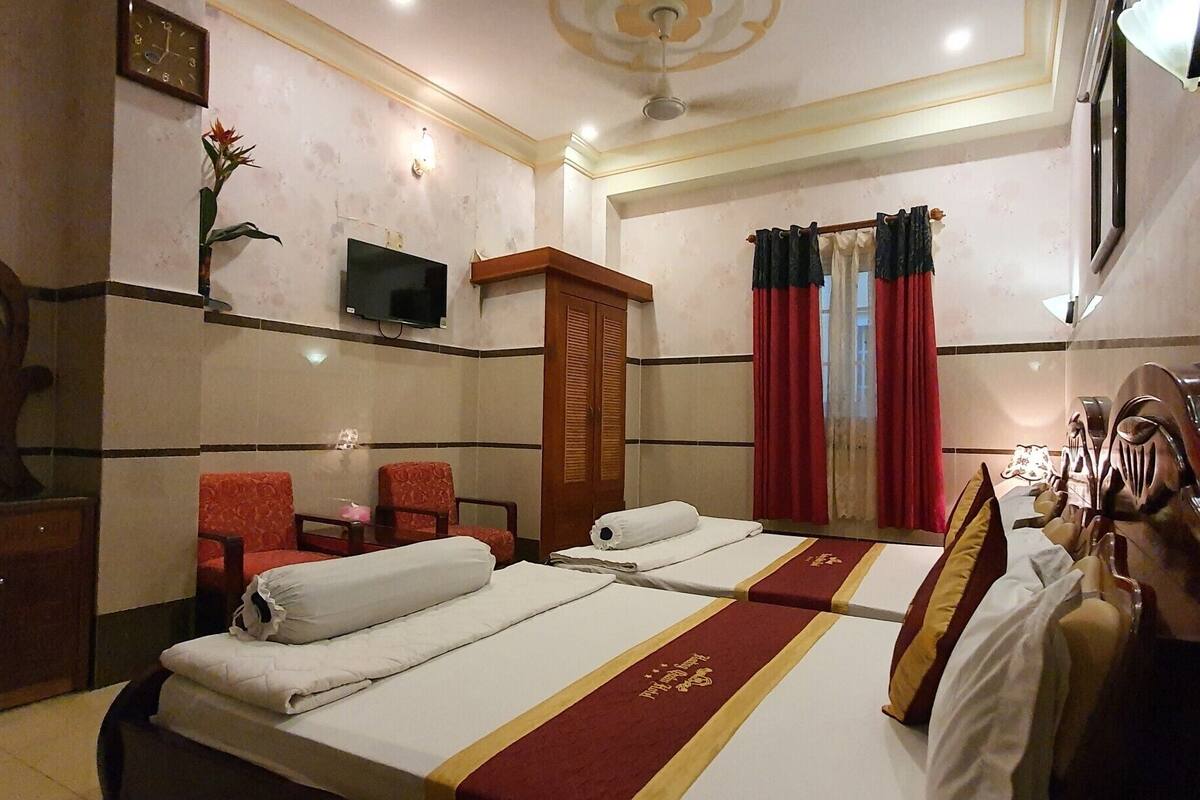 Une chambre d’hôtel avec deux lits, un bureau, une chaise, une télévision et un miroir.