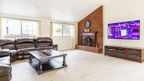 Ein Wohnzimmer mit Ledersofa, Couchtisch, Kamin und Wandfernseher.