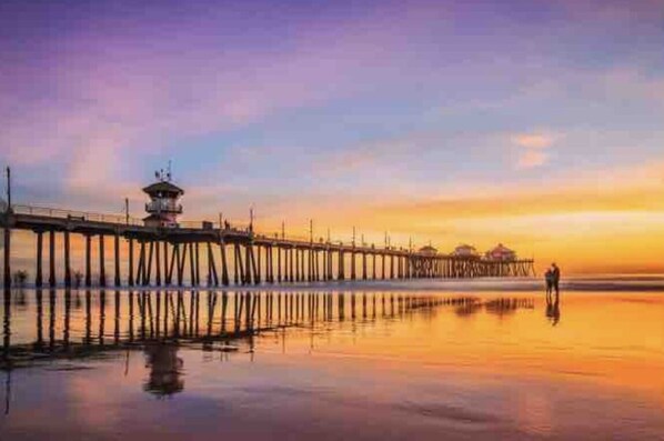 A pier extending into calm waters at sunset with a small structure at the end.