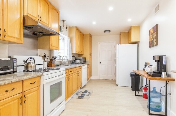 Une cuisine compacte avec des meubles en bois, une cuisinière blanche, un four à micro-ondes et une machine à café.