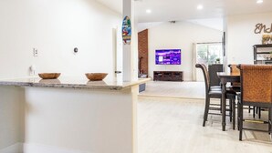 Eine moderne Küche mit einer zentralen Kochinsel, einem Essbereich mit Fernseher und einer Wand mit Ziegelverkleidung.