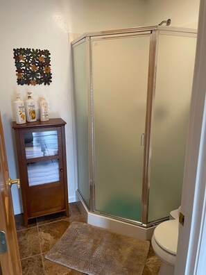 Enjoy a refreshing shower in this bathroom with a glass-enclosed shower stall and convenient storage.
