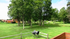 Un espace extérieur verdoyant avec un banc en bois, un barbecue et une clôture en bois.