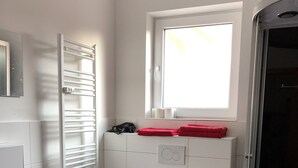 Une salle de bain moderne équipée de toilettes, d’un lavabo et d’un porte-serviettes.