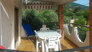 A balcony with a table and chairs, a blue chair, and a red object on the floor. - Holiday Marina di Tertenia 150 meters from the sea IUN P2910 (Tertenia)