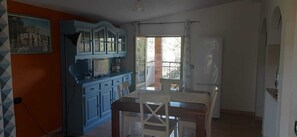 Una cocina con una mesa de comedor y sillas, un armario azul y un ventanal con vistas al exterior.