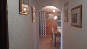 A hallway with framed pictures on the walls, a dining area with a table and chairs, and a patterned wall in the background. - Holiday Marina di Tertenia 150 meters from the sea IUN P2910 (Tertenia)