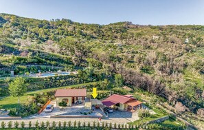 Una propiedad en la ladera de una colina con una casa, una piscina y un jardín.