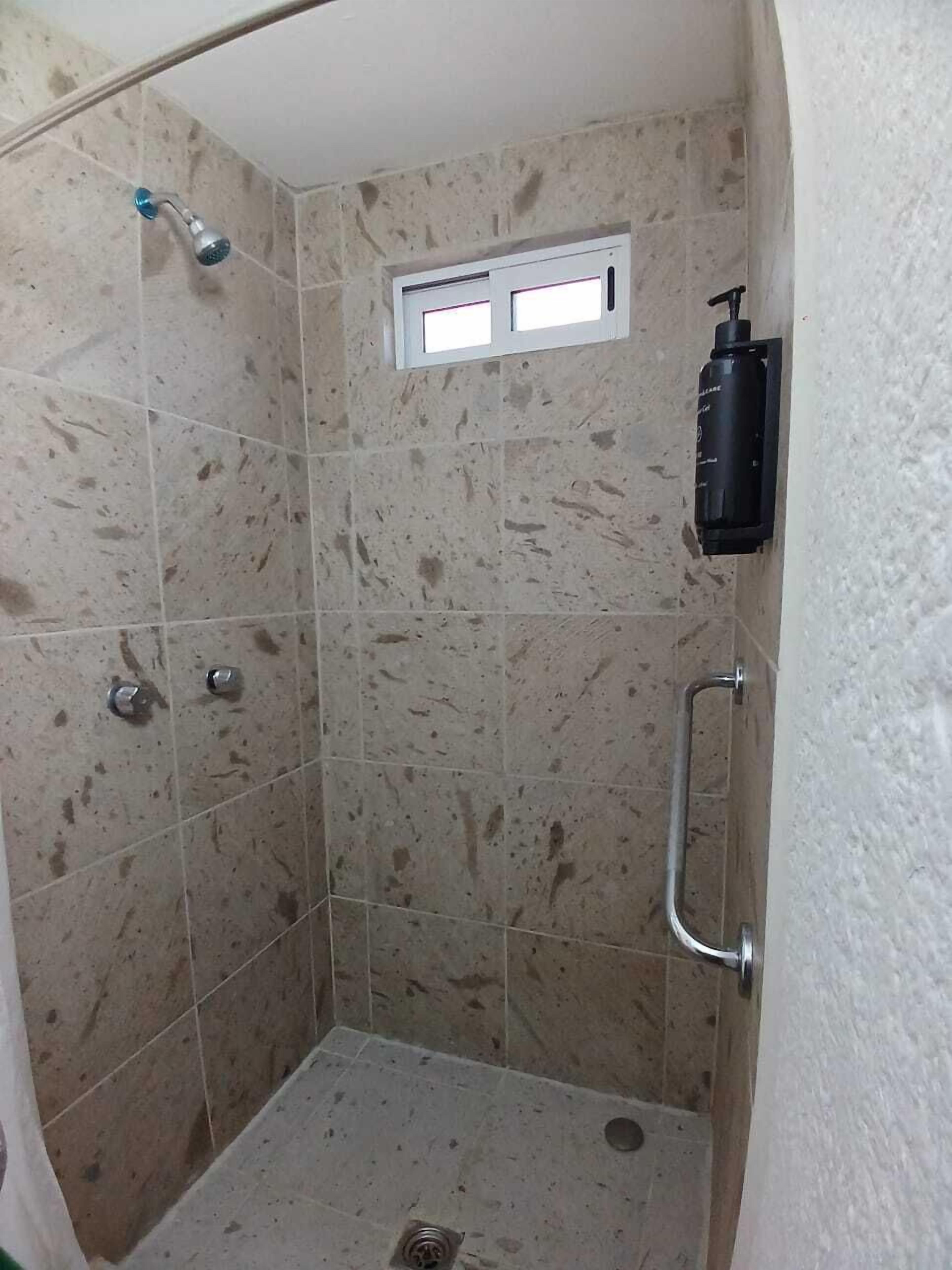 Un box de ducha con ducha de mano y grifo empotrado.