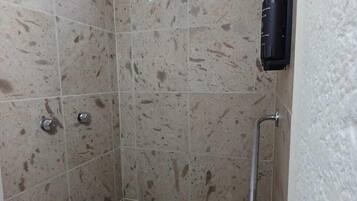 Un box de ducha con ducha de mano y grifo empotrado.