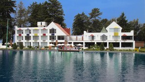 A hotel with a pool, outdoor seating, and a boat.
