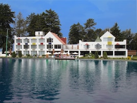Un hotel con piscina, asientos al aire libre y un barco.