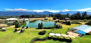 A resort with a large swimming pool, tennis courts, and a mountain backdrop.