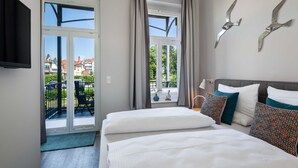 Una habitación de hotel con balcón, cama con ropa de cama blanca y decoración en la pared.