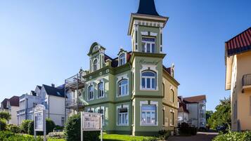 Ein historisches Gebäude mit einem markanten Turm, einem Schild und einem gepflegten Garten.
