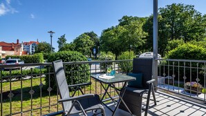 Un área de estar al aire libre con una mesa y sillas, baranda de metal y el hotel 'Hotel Rosenhof' al fondo.
