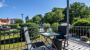 Een terras met een tafel en stoelen, een metalen hekwerk en een uitzicht op Hotel Rosenhof op de achtergrond.