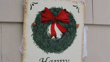 A holiday sign with a red bow and green wreath on a wooden wall.
