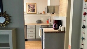 Un corridoio stretto che conduce a una cucina con mobili in legno, un forno a microonde e una macchina da caffè.