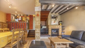 A cozy living room with a wooden dining table, leather sofa, and a fireplace. - Les Oliviers - Great value for money! (Saint-Maximin)
