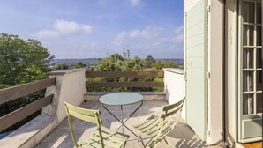 A balcony with a table and two chairs, a wooden railing, and a view of the sea. - Les Oliviers - Great value for money! (Saint-Maximin)