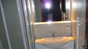 Une petite salle de bain avec un lavabo blanc, des toilettes et un espace douche.