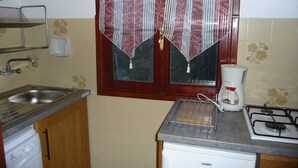 Une cuisine de taille réduite, équipée d’un évier, d’une cuisinière et d’une machine à café.