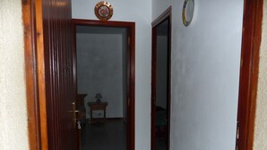 Un couloir avec une porte en bois, une petite table avec une lampe et un miroir accroché au mur.