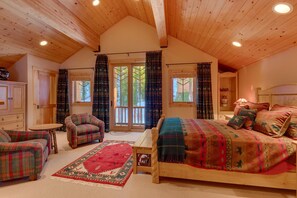 Une chambre confortable avec un grand lit, un canapé, un fauteuil et un plafond en bois.