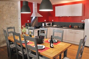 Un espace repas avec une table en bois, des chaises grises et un mur rouge.