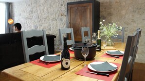 A dining table set with plates, cutlery, a bottle of wine, and a wine glass.