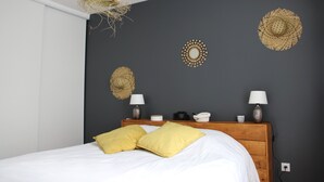 A bedroom with a bed, two lamps, a wooden headboard, and decorative wall hangings.