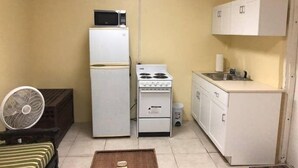 A compact kitchen with a refrigerator, microwave, stove, and sink. - Nature's Comfortable Suite (East End)