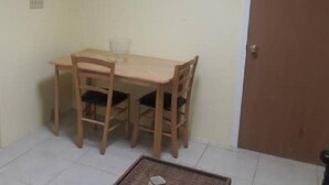 A small room with a wooden table and two chairs, a door, and a framed picture on the wall. - Nature's Comfortable Suite (East End)