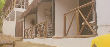Un edificio de dos pisos con techo de paja, barandillas de madera y un objeto amarillo en el suelo.