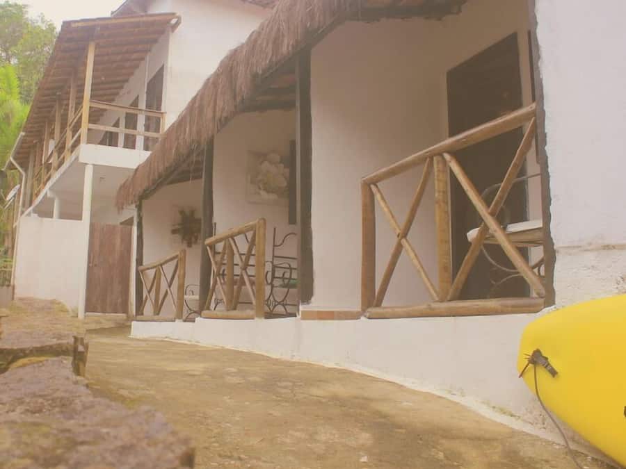 A two-story building with a thatched roof, wooden railings, and a yellow object on the ground.