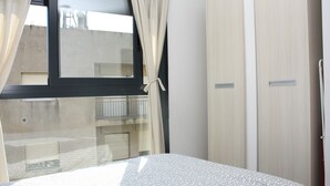 Een slaapkamer met een bed, een raam met gordijnen en een kledingkast.