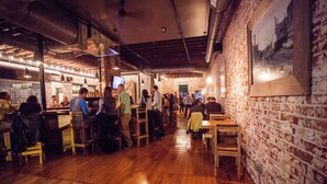 Un restaurante con paredes de ladrillo y suelos de madera, con mesas y sillas dispuestas para comer.