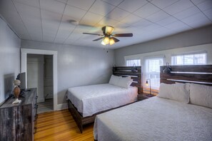 A bedroom with two beds, a ceiling fan, and a wooden dresser. - Big Midtown Home! Sports Room, Bunk Beds! (Omaha)