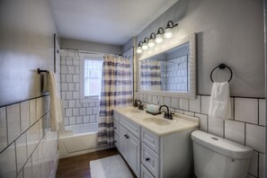A bathroom with a bathtub, a sink with a mirror above it, and a toilet. - Big Midtown Home! Sports Room, Bunk Beds! (Omaha)