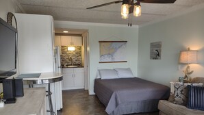 Una habitación de hotel compacta con cama, escritorio, kitchenette y comedor.