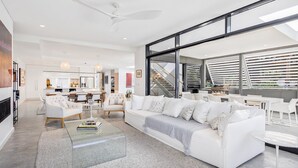 Un salon moderne avec un canapé blanc, une table basse et un coin repas avec des chaises blanches.