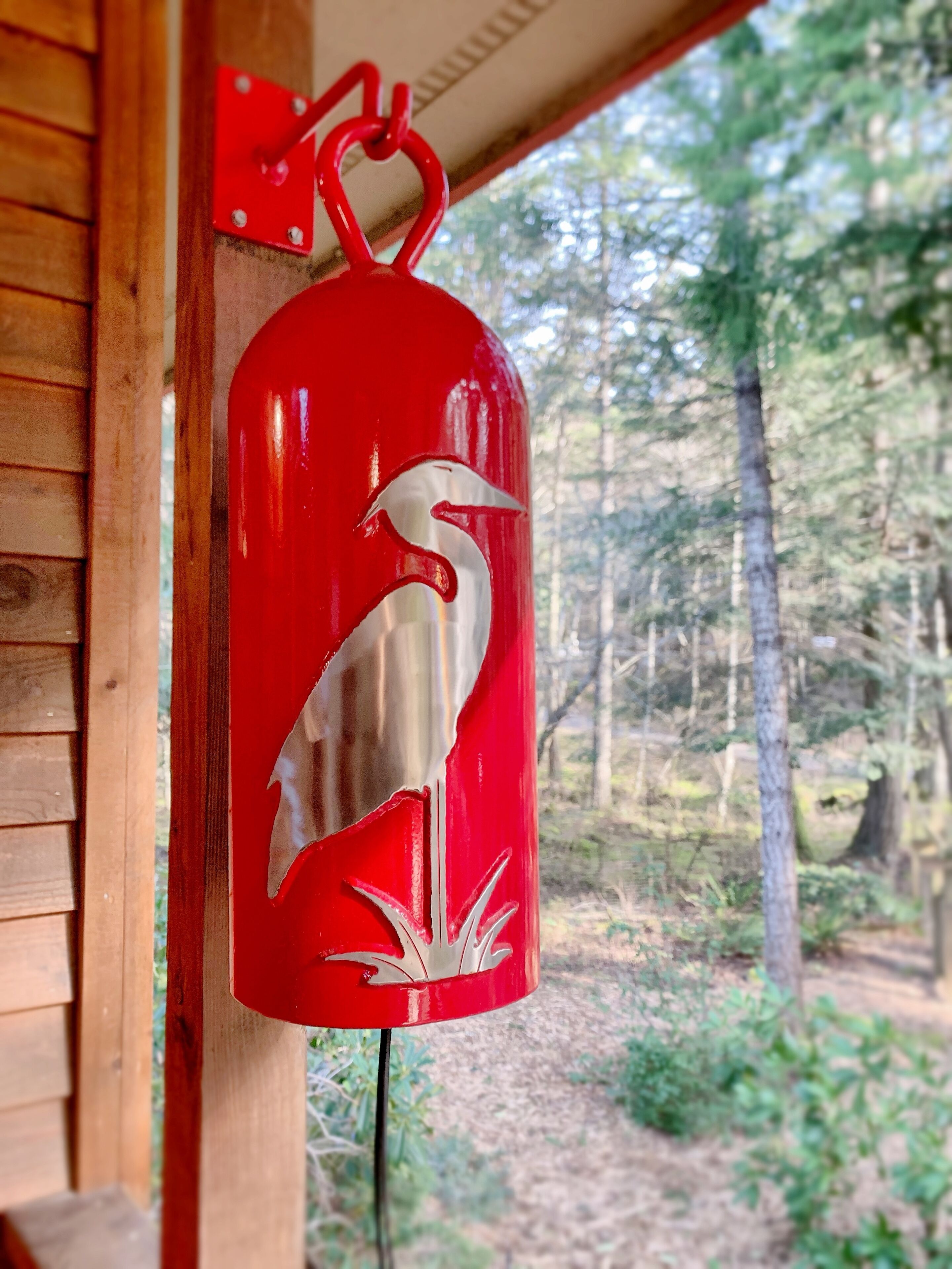 Un extincteur rouge, fixé à un mur en bois et orné d’un motif représentant un oiseau blanc.