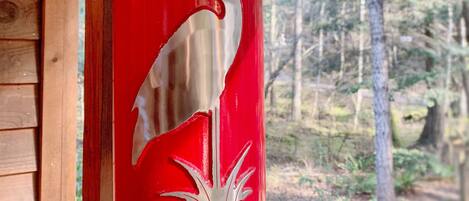Un extincteur rouge, fixé à un mur en bois et orné d’un motif représentant un oiseau blanc.